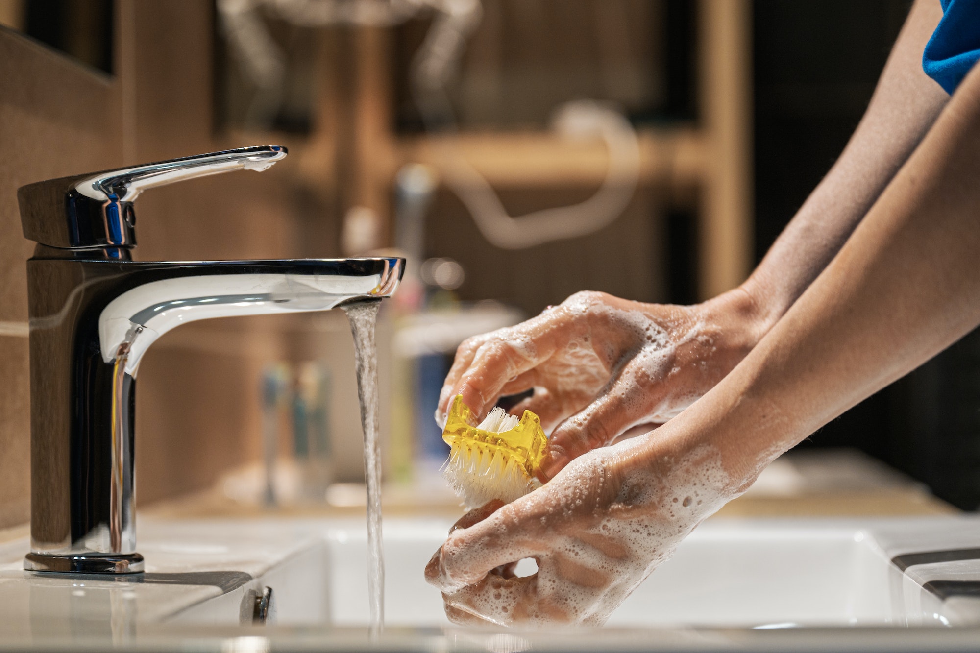 Closeup view of a woman washing her hands with soap and brush